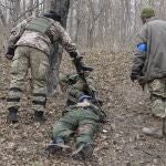 Soldados ucranianos pasan junto al cuerpo de un soldado ruso en la ciudad de Trostsyanets