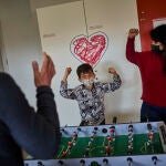 Rubén juega al futbolín con sus padres, Lourdes y Marco, en una sala del Hospital Gregorio Marañón