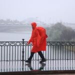 Una persona cruza un puente en Sevilla bajo la lluvia