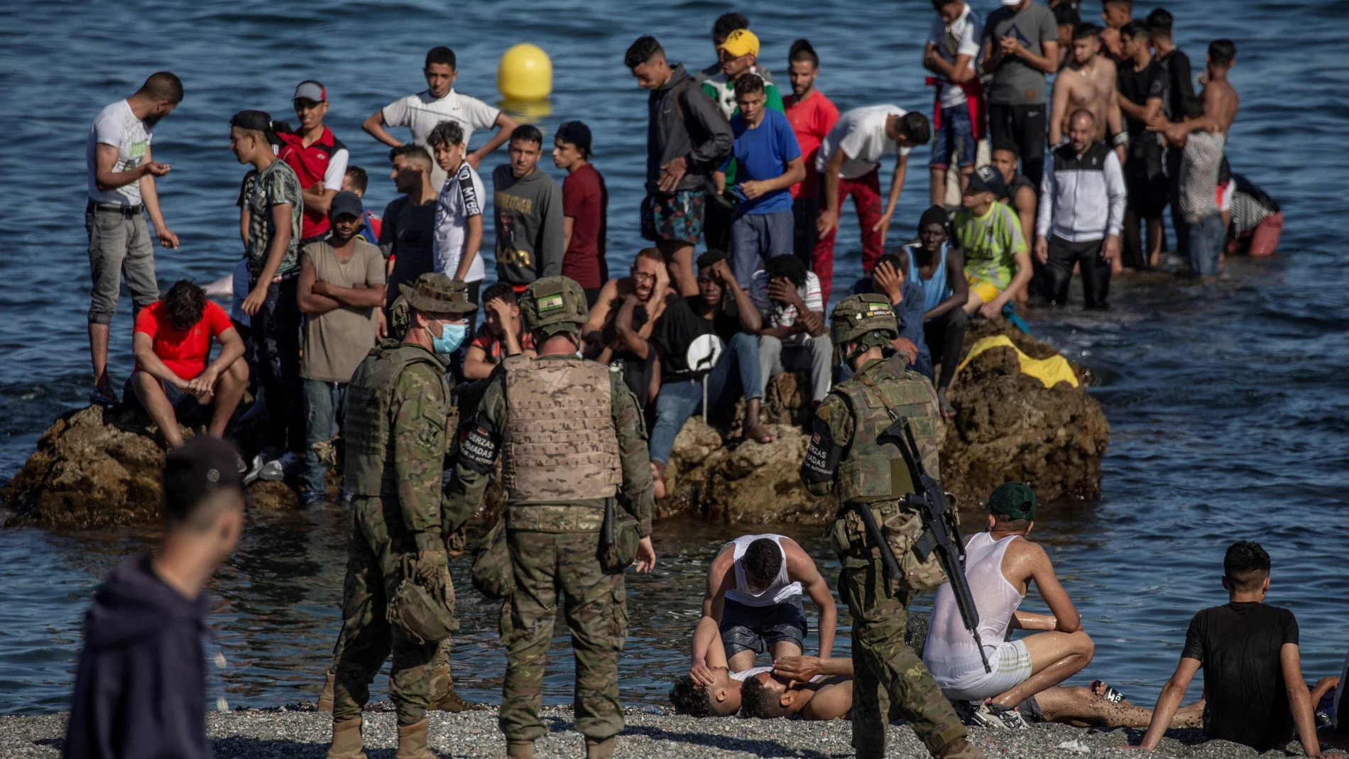 Soldados del Ejército de Tierra observan cómo un grupo de inmigrantes alcanzan la playa fronteriza de El Tarajal de Ceuta, el pasado julio