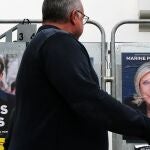 Un hombre pasea frente a los carteles de Le Pen y de Macron en Francia