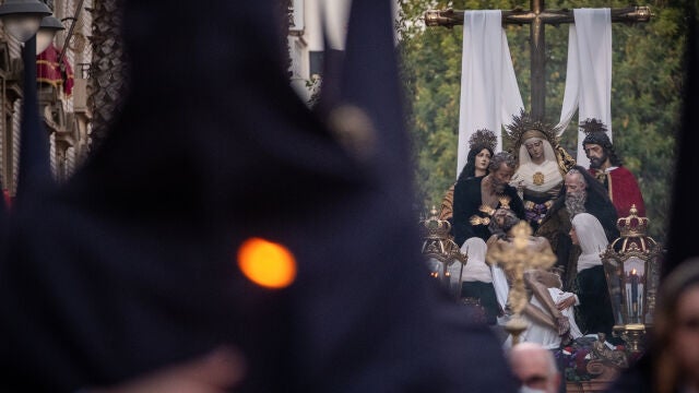 Un nazareno acompaña, el Miércoles Santo, al paso de la Cofradía de la Santa Cruz por las calles de Huelva