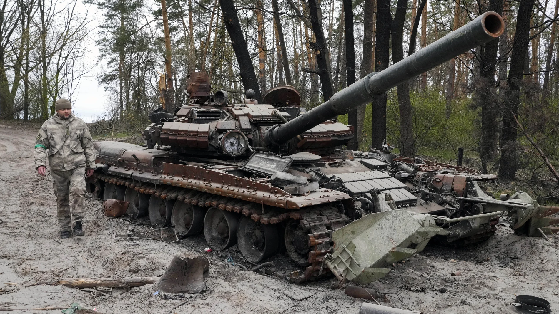 Un soldado ucraniano pasa junto a un carro de combate ruso destruido por los combates en Moshchun, cerca de Kiev