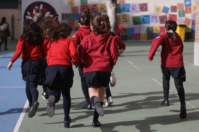 Un grupo de niños corren en el patio de un colegio