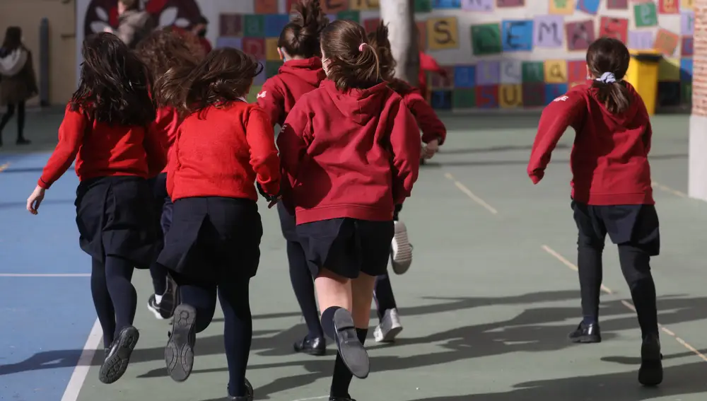 Un grupo de niños corren en el patio de un colegio