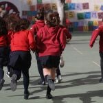 Un grupo de niños corren en el patio de un colegio