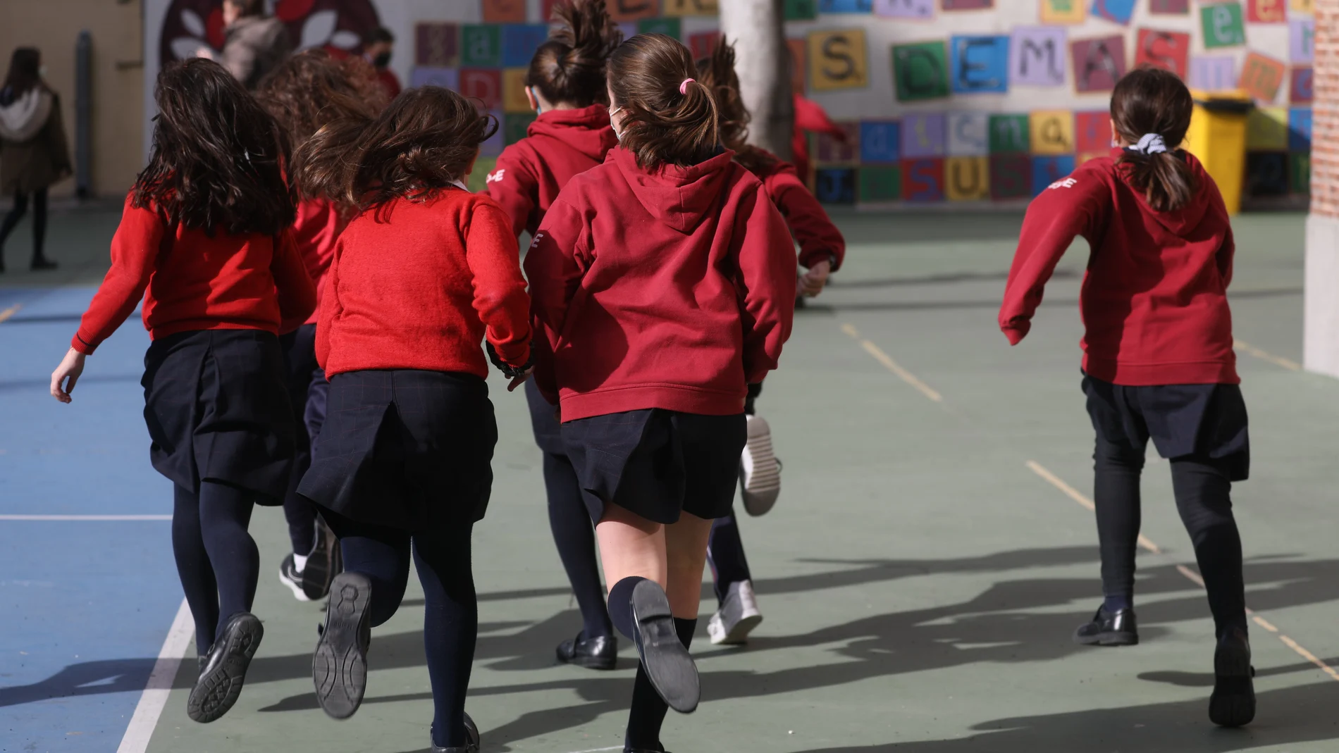 Un grupo de niños corren en el patio de un colegio