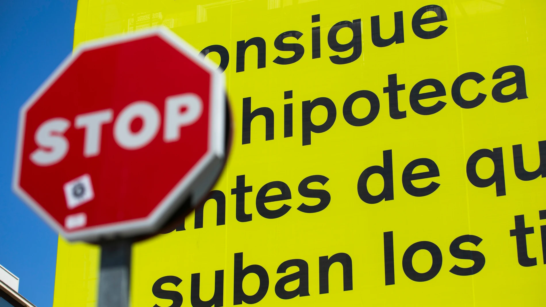 Cartel publicitario de Idealista que reza "consigue tu hipoteca antes de que suban los tipos" junto a una señal de Stop