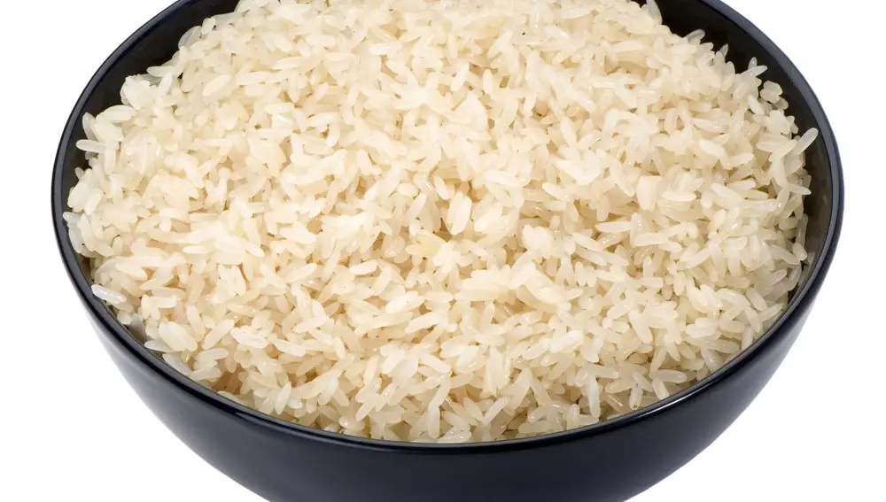 Arroz hervido en un primer plano de tazón negro aislado en blanco | Fuente: Dreamstime