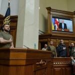 El primer ministro de Reino Unido, Boris Johnson, conectado por videoconferencia, y el presidente ucraniano, Volodimir Zelenski, durante el himno nacional ucraniano en la Rada Suprema