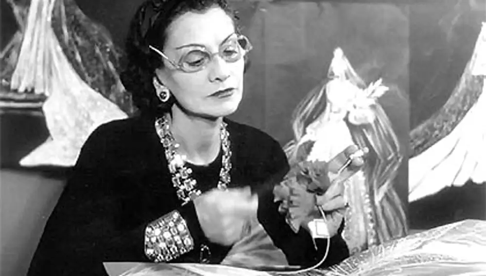 Coco Chanel en su taller rodeada de sus colecciones y bocetos de sus trajes.