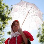 Una mujer vestida de chulapa se protege del sol con un paraguas en los alrededores de la Ermita del Santo