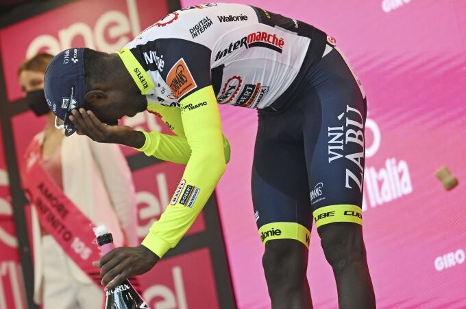 Biniam Girmay se lleva la mano al ojo después de golpearse con el tapón del champán