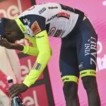 Biniam Girmay se lleva la mano al ojo después de golpearse con el tapón del champán