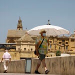 Una persona se protege con una sombrilla del intenso calor mientras pasea por el puente romano de Córdoba