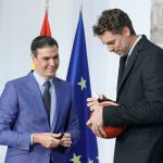 El exjugador de baloncesto Pau Gasol (d) firma este jueves un balón al presidente del Gobierno, Pedro Sánchez, durante el acto de entrega de la Gran Cruz de la Real Orden del Mérito Deportivo