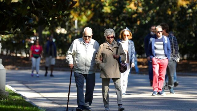 Pensionistas paseando por un parque.