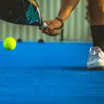 A young paddle tennis player catching the ball with the racket - Sportsman playing padel game