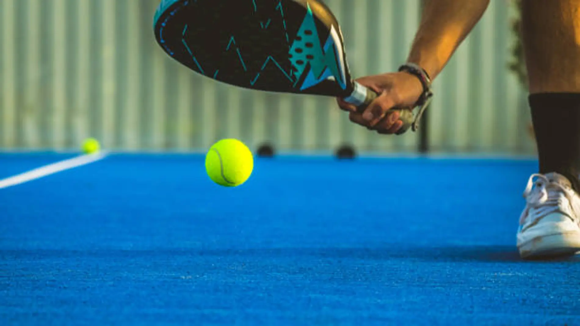 A young paddle tennis player catching the ball with the racket - Sportsman playing padel game