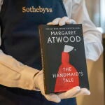 La copia ignífuga de "El cuento de la criada", sostenida por una empleada de Sotheby's