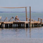 Una mujer se refresca el cuerpo con agua mientras toma el sol en la playa de los Urrutias, en el Mar Menor.