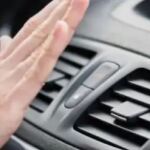 En la imagen, una mano sobre el aire acondicionado de un coche