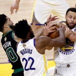 Andrew Wiggins, el mejor jugador de los Warriors en el quinto partido, trata de hacerse con el balón en presencia de Tatum y Curry