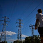 Una persona pasa junto a unas torres de alta tensión en la ciudad de Madrid
