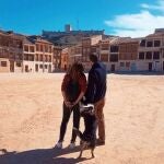 Una pareja con su perro contempla la vista del castillo de Peñafiel desde la Plaza del Coso