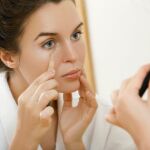 Mujer aplicando corrector de ojeras.