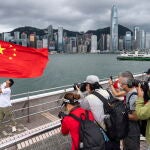 Un pobre posa con una bandera china en el Victoria Harbour de Hong Kong, en China