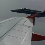 Un avión F-18 vuela cerca de las distintivas puntas de las alas naranjas del avión A-319 de EasyJet