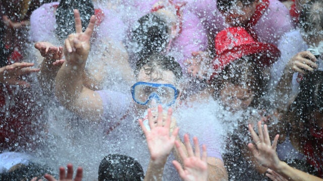 Un grupo de jóvenes se moja con agua tras el chupinazo en la Plaza Consistorial de Pamplona e