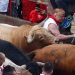 Un mozo es alcanzado por uno de los toros de la ganadería gaditana Núñez del Cuvillo a su llegada a la curva de la calle Estafeta