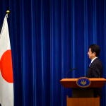 Shinzo Abe posa frente a la bandera nacional en la residencia del primer ministro en Tokio en 2013