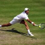 Novak Djokovic se estira para llegar a una bola en la final de Wimbledon 2022 contra Kyrgios