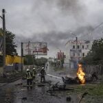Los equipos de rescate tratan de sofocar el fuego de un automóvil destruido tras un ataque ruso en un barrio residencial en el centro de Jarkiv