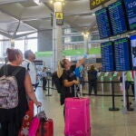 Varias personas miran los paneles informativos de los vuelos en la Terminal 3 de salidas del aeropuerto de Málaga. EFE/Álvaro Cabrera