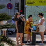 Unas turistas se refrescan en una fuente junto a un plano de la ciudad de Sevilla. EFE/Julio Muñoz