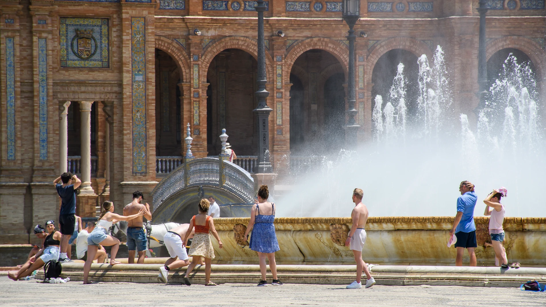 Varios turistas se refrescan en la fuente de la Plaza de España de Sevilla. EFE/ Raúl Caro.