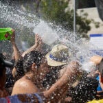 Varias personas disfrutan del agua durante la celebración de la Batalla Naval, uno de los atractivos de las Fiestas Patronales de la Virgen del Carmen en el distrito de Puente de Vallecas
