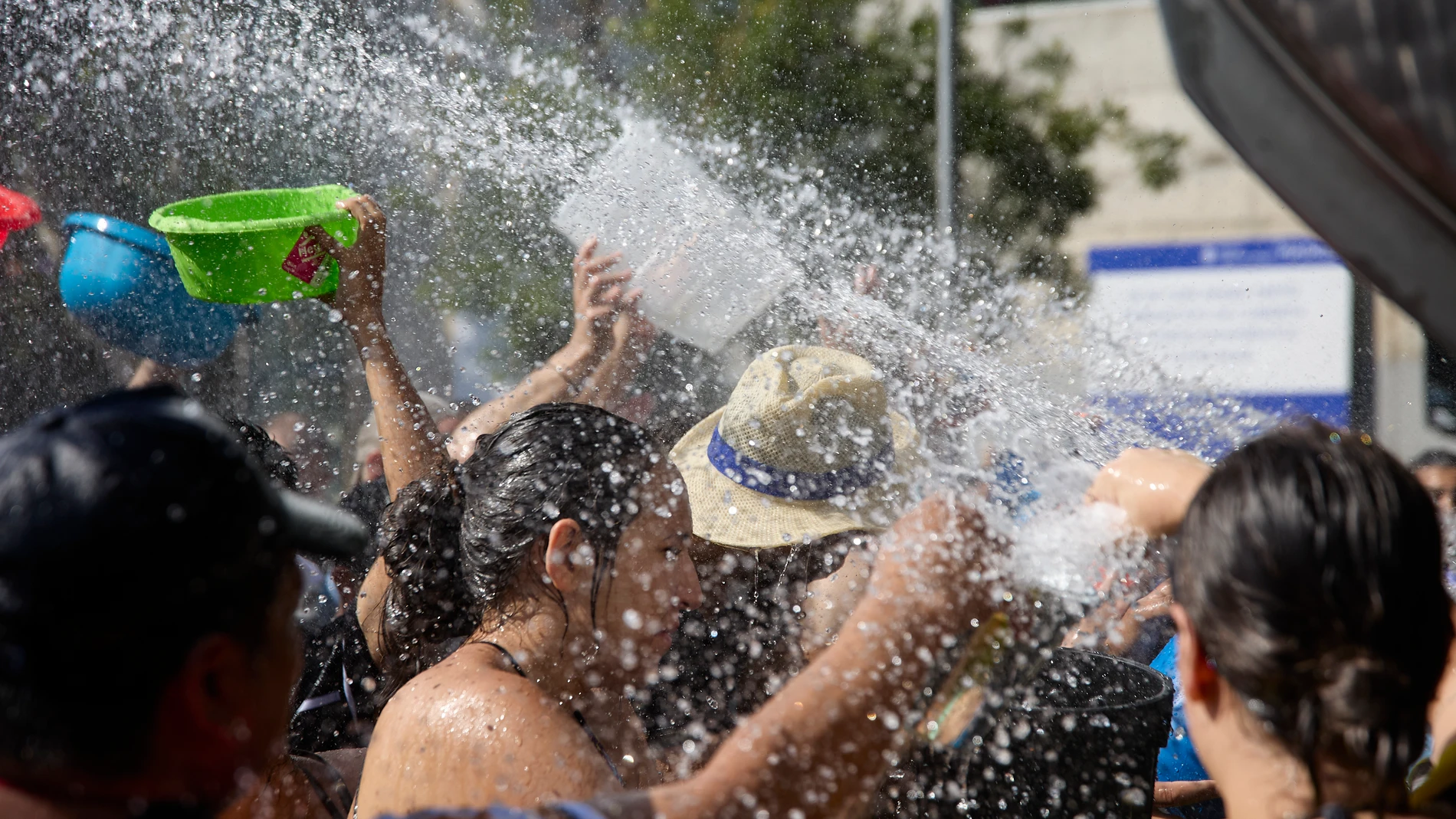 Varias personas disfrutan del agua durante la celebración de la Batalla Naval, uno de los atractivos de las Fiestas Patronales de la Virgen del Carmen en el distrito de Puente de Vallecas