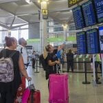 Varias personas miran los paneles informativos de los vuelos en la Terminal 3 de salidas del aeropuerto de Málaga. EFE/Álvaro Cabrera