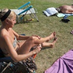 Una mujer se aplica crema solar en una piscina de Palencia