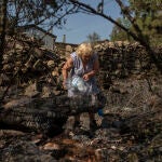 Una mujer echa agua en una zona vegetal afectada por el incendio en Ferreras de Abajo, Zamora