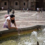 Una mujer se refresca en una fuente del centro histórico de Valencia
