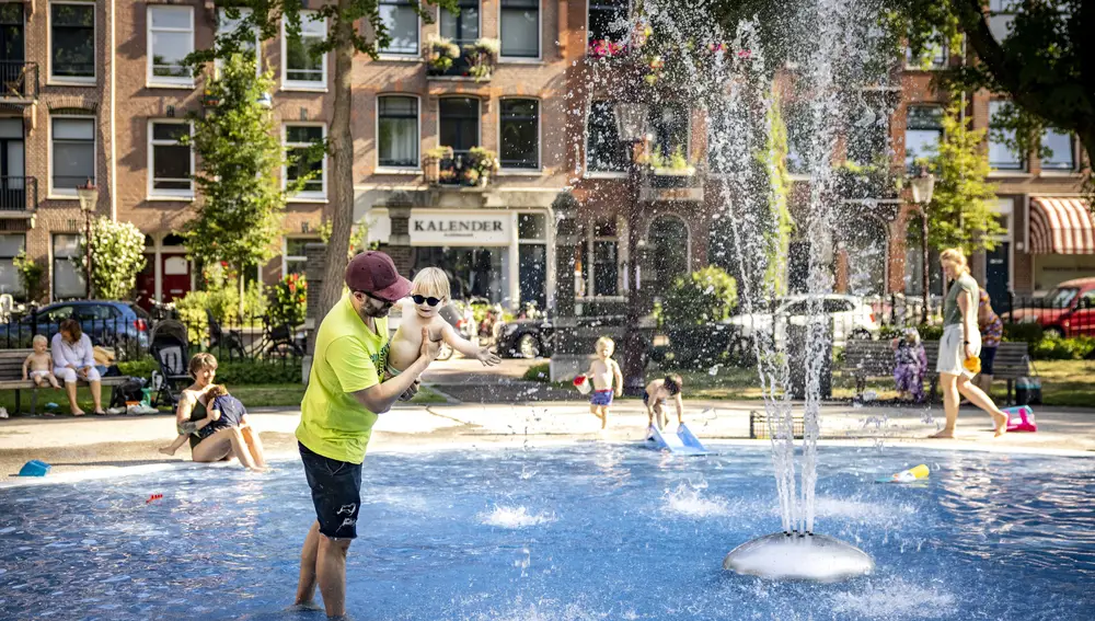 -FOTODELDIA- Ámsterdam (Países Bajos), 19/07/2022.- Padres y madres se refrescan con sus hijos en una fuente en Bellamyplein, en Ámsterdam, Países Bajos, 19 de julio de 2022. Debido a las altas temperaturas que se prevé suban hasta los 38 o 39 grados centígrados , el Real Instituto Meteorológico de los Países Bajos (KNMI) emitió un 'código naranja' hasta el 20 de julio y advirtió especialmente a 'los ancianos, los niños pequeños y las personas con salud delicada' de las consecuencias para la salud. EFE/RAMON VAN FLYMEN
