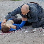El padre del niño de 13 años se arrodilla para sostener la mano de su hijo fallecido en Jarkiv