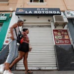 En la imagen dos mujeres pasan ante la puerta del bar donde ocurrió la agresión