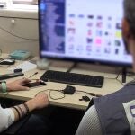 Dos agentes de la Policía Nacional investigan un ordenador